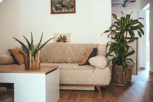 Salon de cottage tropical avec mobilier crème, plantes en pots et accents bois chez ART DE VOYAGER à Étretat