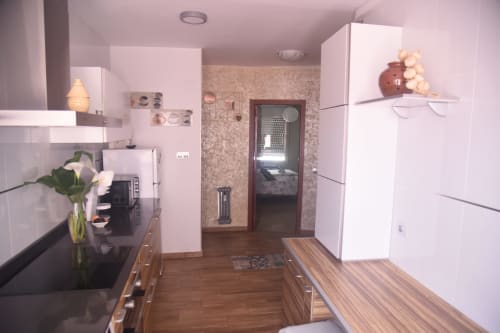 Modern kitchen in Benavente apartment with white cabinetry, wooden counters, and appliances
