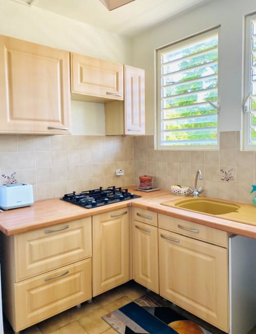 Cuisine lumineuse avec armoires en bois, cuisinière à gaz et évier à l'appartement Maisons En Or à Cayenne