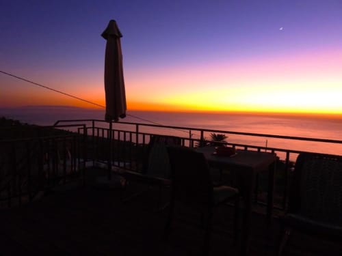 Vista del atardecer desde la terraza de la villa en Rural La Palma, Tijarafe, con horizonte oceánico y silueta de sombrilla al anochecer.