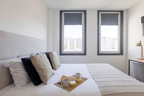 Estúdio moderno compacto no hotel do Porto com roupa de cama branca, vista para a cidade, bandeja de café da manhã na cama