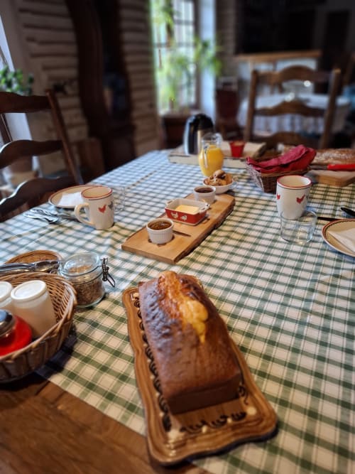 Breakfast table at Les Gravets B&B in Sigalens with bread, coffee, and juice on checkered tablecloth