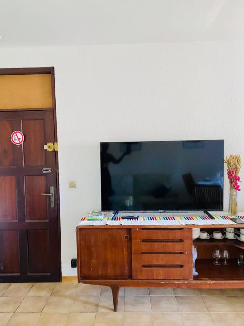 Salon moderne d'un appartement avec téléviseur écran plat, meubles en bois et panneau non-fumeur à la porte à Cayenne, Guyane