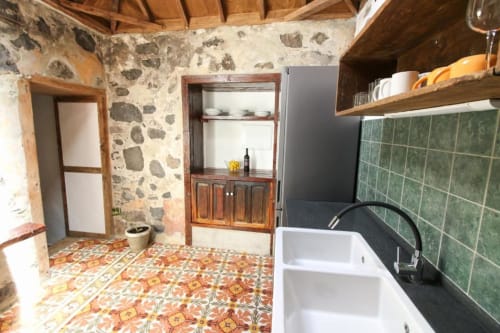 Cocina rústica en Casa 1820, Rural La Palma, con piso de azulejos coloridos, salpicadero verde, muebles de madera y fregadero blanco
