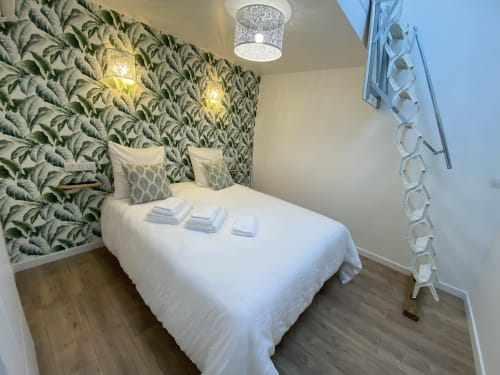 Modern bedroom at La Maison Blanche in Bouguenais with tropical leaf wallpaper, white bed, and garden view