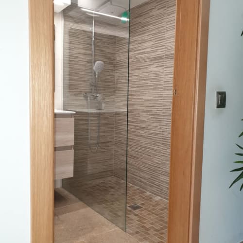 Moderno baño con ducha a ras de suelo, mamparas de vidrio y baldosas tipo madera en Hostal El Molino, Collado Villalba