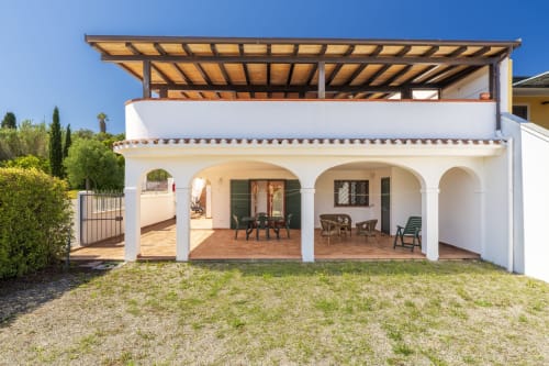 Appartamento bianco mediterraneo con veranda ad archi, pergolato in legno, patio arredato e vista sul giardino a Bari Sardo