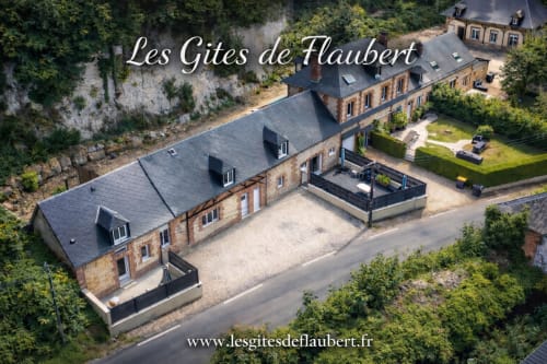 Aerial view of Les Gites de Flaubert stone villa with black roof, gardens and tree-lined grounds in Le Héron, France