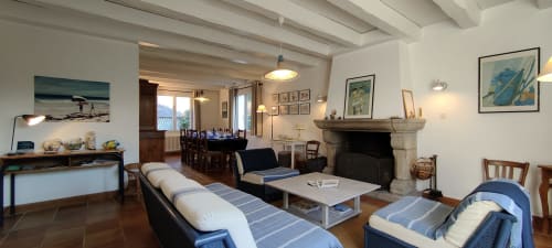 Spacieux séjour de villa à Mer et Maisons avec canapés bleus rayés, cheminée, salle à manger et vue sur le jardin à La Trinité