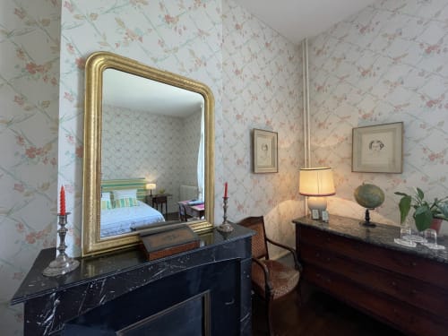Chambre élégante du Château de Vaux Morvan avec miroir doré, papier peint à motifs floraux et commode en marbre noir