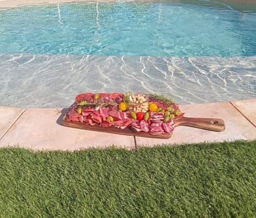 Plateau de charcuterie au bord de la piscine du gîte Chez Laure & Marc à Plaissan, avec eau cristalline et vue sur le jardin