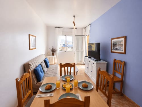 Dining area in Apartamento Lateral at Apartamentos El Calón Playa with sea view, wooden table, chairs, and sofa bed