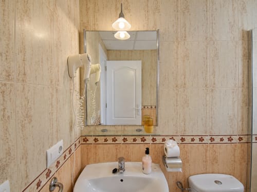 Cuarto de baño de Apartamentos El Calón Playa con paredes alicatadas, lavamanos, espejo e inodoro en Cuevas del Almanzora