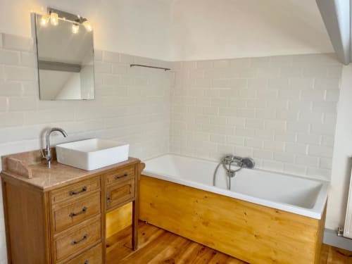 Salle de bain moderne au Château de Vaux Morvan avec meuble vasque en bois, carrelage blanc et baignoire îlot