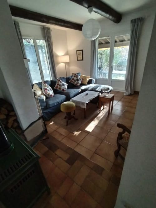 Bright living room with blue sofa, floral cushions, wooden floors, and garden views through French doors at dog-friendly
