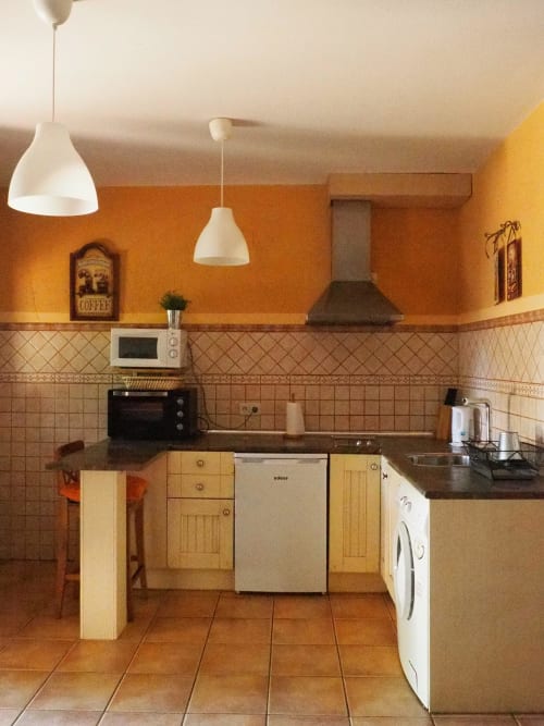 Cocina en Apartamentos Senda del Duratón con paredes naranjas, muebles de madera, encimeras negras y electrodomésticos modernos
