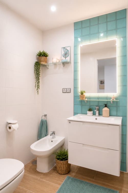 Salle de bain moderne dans l'appartement Sara & Gino Fuerteventura avec carrelage turquoise, miroir éclairé, meuble blanc et bidet