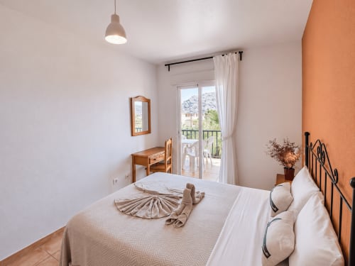 Bright bedroom at Apartamentos El Calón Playa with sea view, wooden furniture, and balcony access in Cuevas del Almanzora