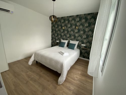Chambre moderne de l'appartement La Maison Blanche avec lit queen, mur d'accent à motifs, parquet et suspension