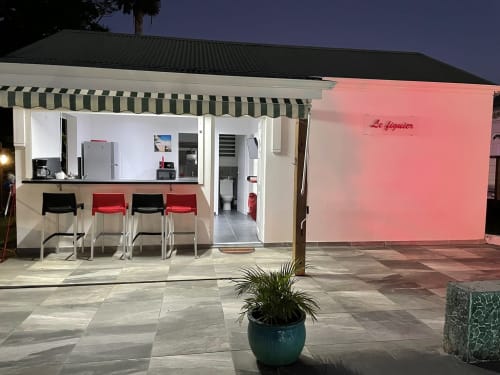 Le Figuier, gîte de Kaz A Bibi à Sainte-Rose en Guadeloupe, avec murs roses, auvent rayé et espace de détente extérieur