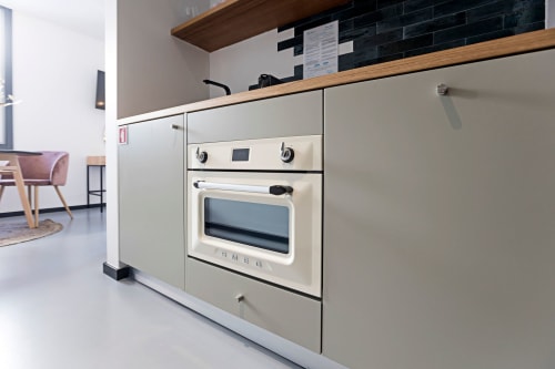 Kitchenette moderna em estúdio de hotel no Porto com armários creme, bancada de madeira e forno embutido na Benefit Collection