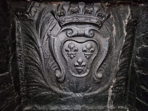 Ornate stone coat of arms with fleur-de-lis shield and crown, architectural detail at Villa République Normandie in Caen