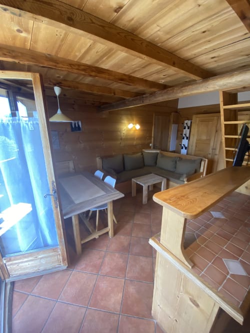 Intérieur moderne de La Ferme des Georgières avec poutres en bois, kitchenette, coin repas et séjour gris