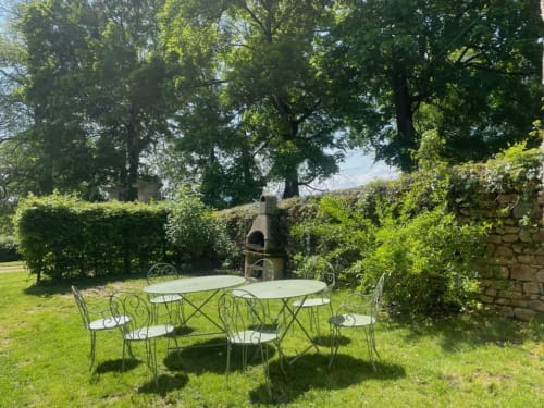 Salon de jardin extérieur au cottage Château de Vaux Morvan avec mobilier en fer forgé et haies couvertes de lierre