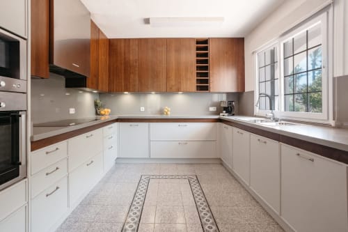 Cocina moderna con gabinetes de madera, muebles bajos blancos, encimeras oscuras y amplia ventana con vistas al jardín en Las