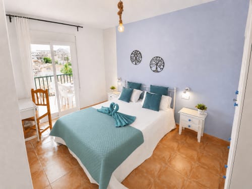 Bright bedroom at Apartamentos El Calón Playa with teal bedding, balcony overlooking Cuevas del Almanzora, and sea-view