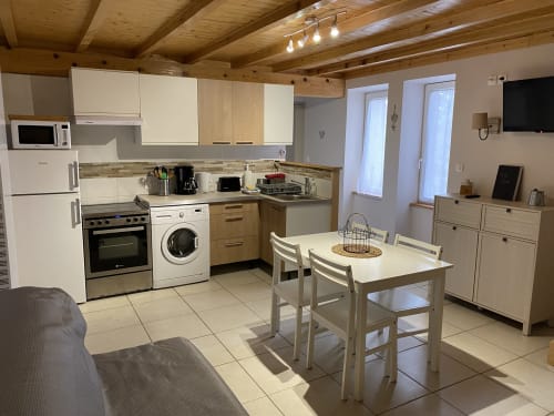 Cuisine cottage moderne et salle à manger au Cocon De Curson avec armoires blanches, appareils en acier inoxydable et bois