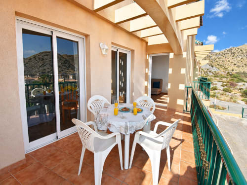 Sunny terrace at Apartamentos El Calón Playa with white furniture, sea view, and hillside landscape in Cuevas del Almanzora
