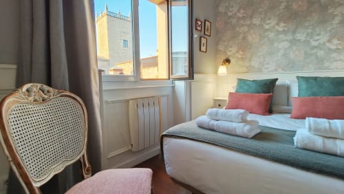 Elegante habitación del hotel Mirador Medieval en Cáceres con vistas al patrimonio, cama decorada y muebles clásicos