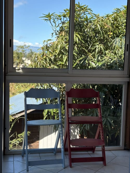 Deux chaises en bois face au jardin à La Villa Maraloupia aux Avirons, entourées de plantes luxuriantes et vue sur la mer