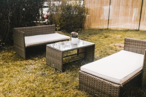 Salon de jardin en rotin avec coussins blancs dans le jardin du gîte Bobochic, Étretat