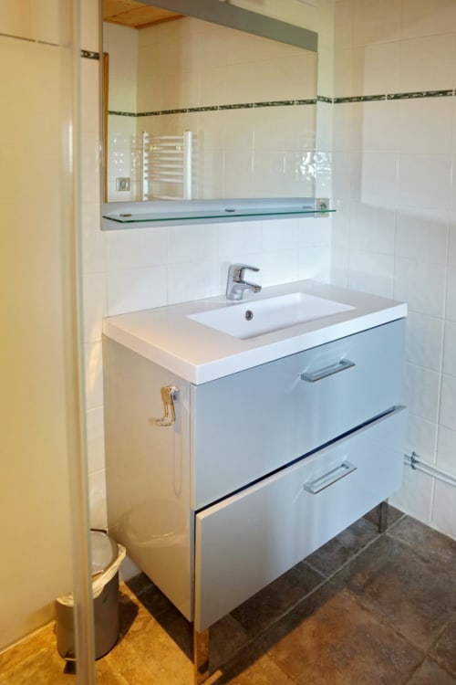 Modern bathroom in Petit Loup room at Chalet La Louvière with white vanity, sink, and mirror