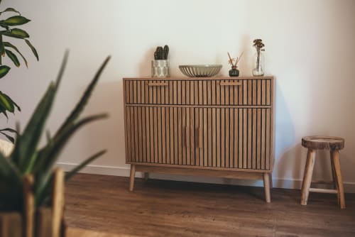 Commode en bois de style années 50 avec portes rayées, plantes décoratives et accessoires dans la chambre jardin tropical des Tropiques à ART