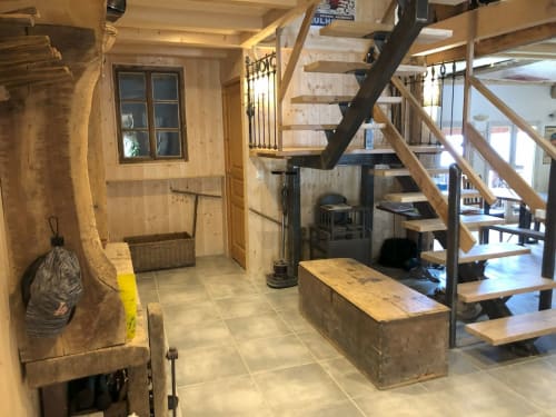 Modern cottage interior with wooden walls, stone staircase, wood-burning stove, and rustic kitchen counter at Les Chalets de