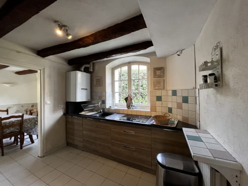 Cuisine moderne du Cottage Jardin à Aux Fleurs de Cerises avec mobilier noir, plan de travail sombre et fenêtre cintrée