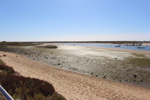 Tavira coastal bay at Break Lovers with sandy beach, moored boats, and blue water under clear sky