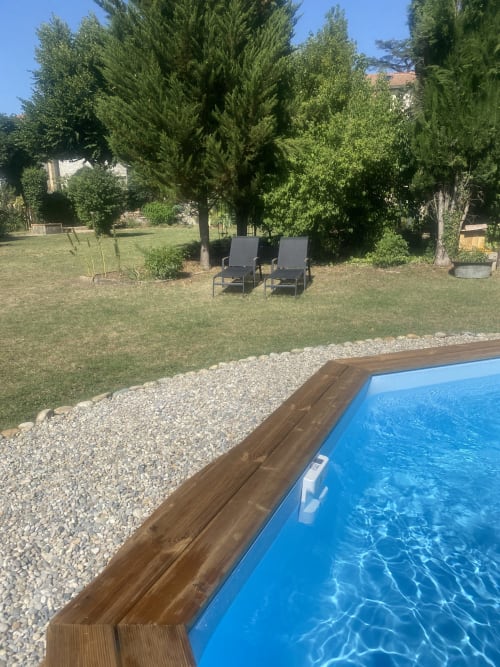 Espace piscine et jardin du gîte Le Cocon De Curson avec transats sous les cyprès