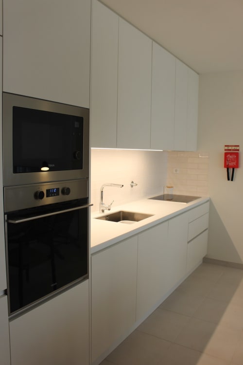 Modern kitchen with white cabinetry, stainless steel appliances, and minimalist design at Break Lovers apartment in Tavira