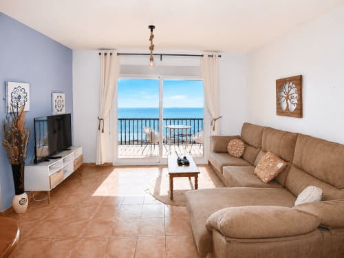 Bright beachfront apartment living room with sea views, tan sofa, and modern furnishings in Cuevas del Almanzora