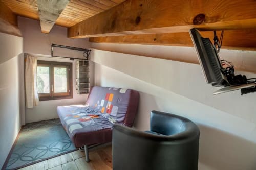 Acogedora habitación en loft con vigas de madera, sofá cama, sillón, TV y vistas a la montaña en Montgat Prepirineo