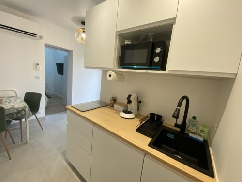 Modern kitchen in La Maison Blanche apartment, Bouguenais, with black sink, microwave, and wooden countertop
