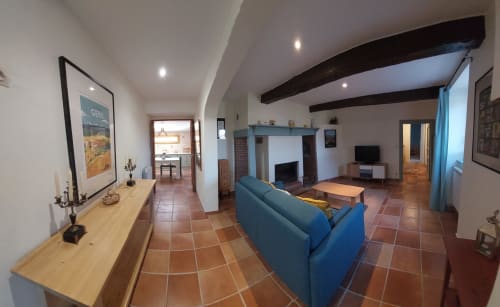 Spacious living room at Orchids cottage, Les Gites de Campardon, with blue sofa, fireplace, terracotta tiles, and garden
