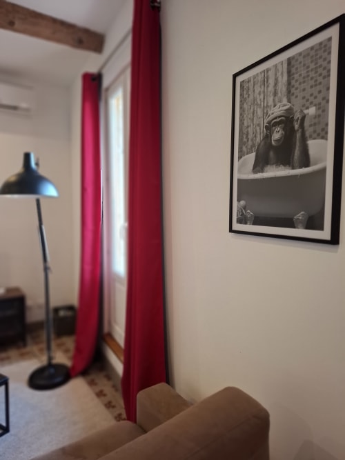 Intérieur moderne de Chez Laure & Marc avec tableau de chimpanzé, rideaux rouges, lampadaire noir et canapé beige