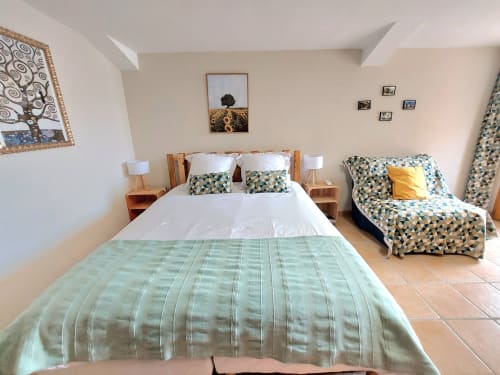 Bright bedroom at Les Gites de Campardon with two beds featuring geometric patterned bedding, wooden nightstands, and garden