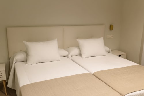 Dos camas gemelas con ropa blanca y cabecero beige en Hotel Boutique Alcazaba Salobrena