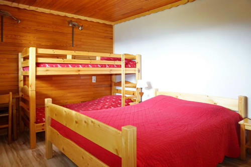 Wooden bedroom at Chalet La Louvière with bunk bed and single bed with red bedding, mountain view room Petit Loup